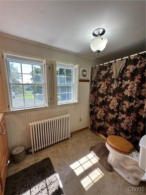 bathroom with curtained shower, radiator, toilet, wainscoting, and wood walls