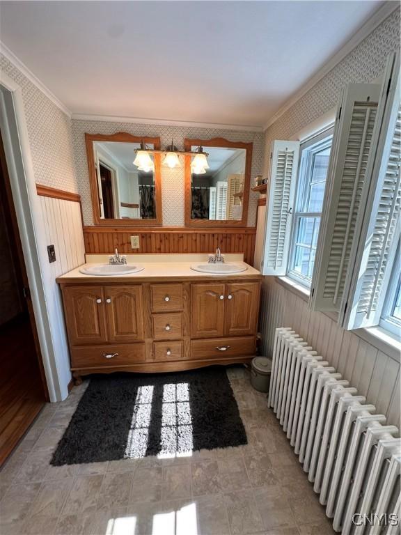 full bathroom featuring wallpapered walls, radiator heating unit, a sink, and wainscoting