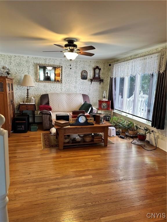 living room featuring wood finished floors, ceiling fan, and wallpapered walls