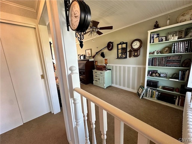 hallway featuring carpet floors, ornamental molding, and an upstairs landing