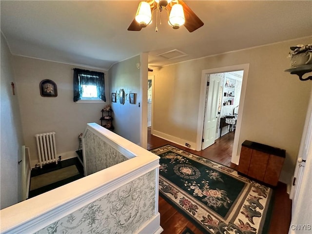 corridor with dark wood-style floors, radiator heating unit, attic access, and baseboards