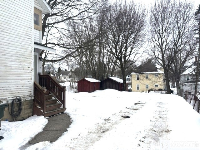 snowy yard with an outdoor structure and a shed