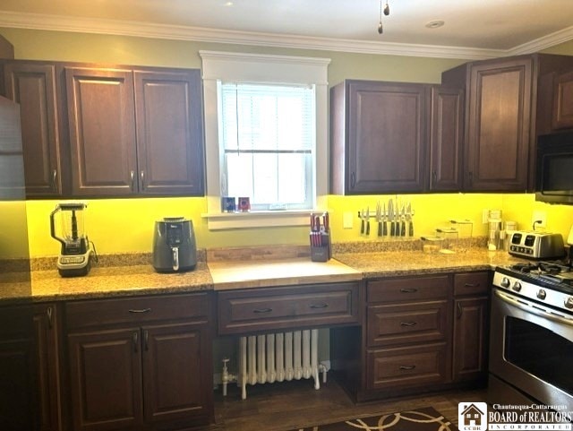 kitchen with radiator heating unit, crown molding, black microwave, and stainless steel range with gas stovetop