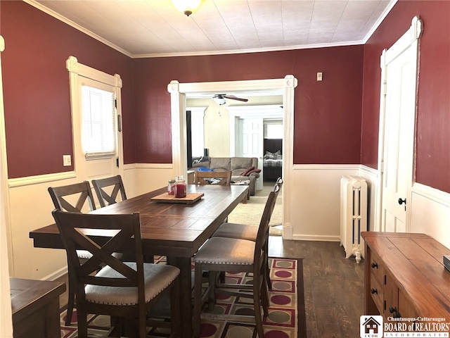 dining area with dark wood-type flooring, radiator, wainscoting, and crown molding