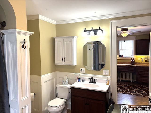 bathroom with toilet, a wainscoted wall, vanity, radiator heating unit, and crown molding