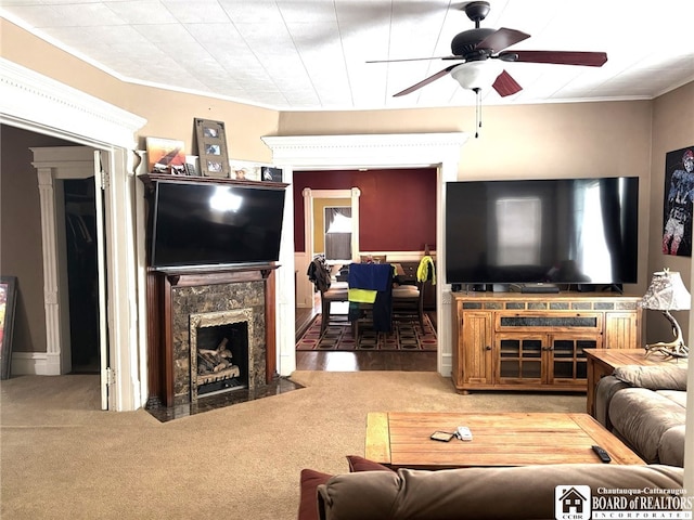 carpeted living area with a ceiling fan, a high end fireplace, and ornamental molding