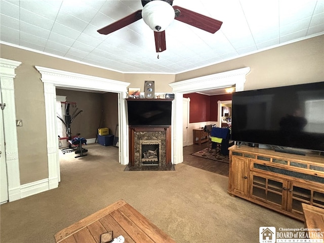 carpeted living room with a high end fireplace and a ceiling fan