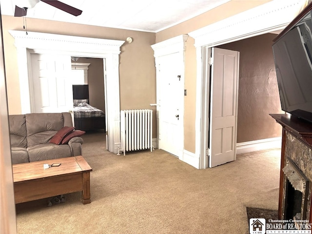 carpeted living room with radiator, a fireplace, ceiling fan, and baseboards