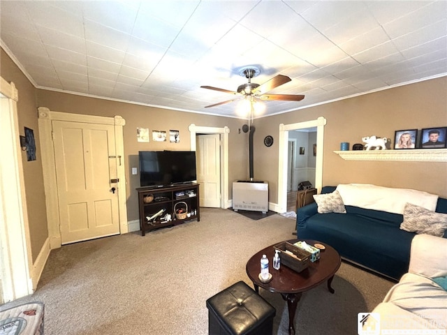 living room featuring carpet floors, ceiling fan, baseboards, and ornamental molding