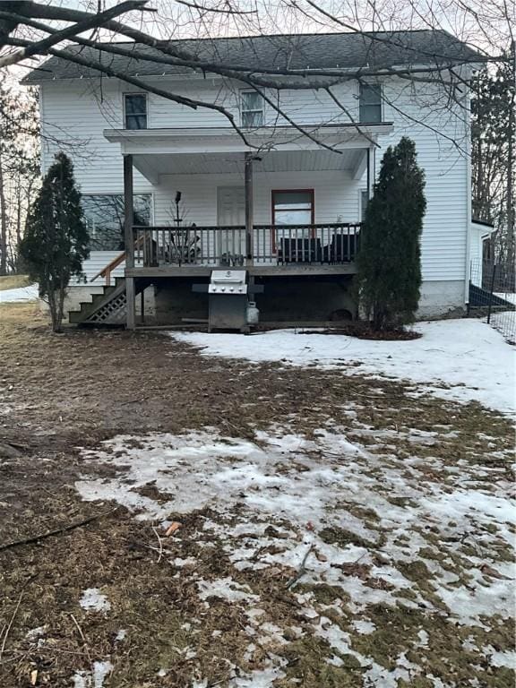 snow covered back of property with covered porch