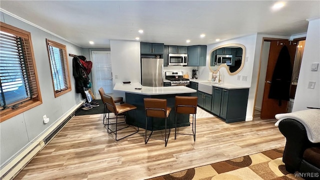 kitchen with a breakfast bar area, light countertops, appliances with stainless steel finishes, a sink, and light wood-type flooring