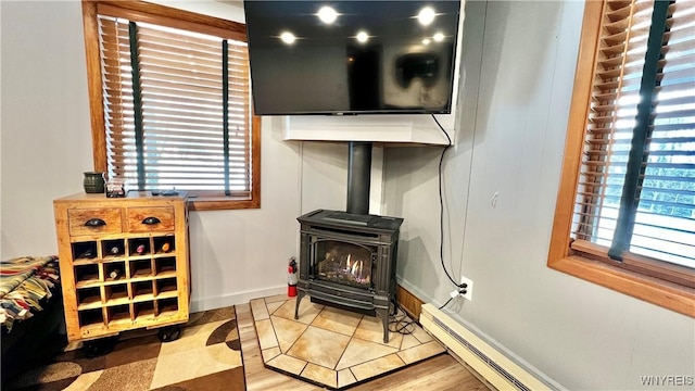 details with a baseboard radiator, a wood stove, and baseboards