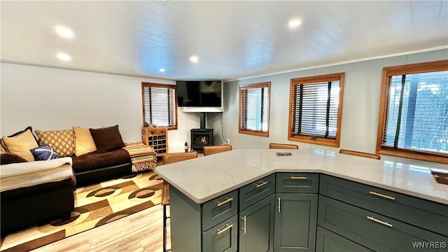 kitchen with light stone counters, recessed lighting, light wood-style floors, open floor plan, and a wood stove