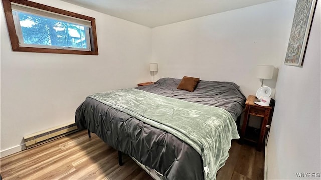 bedroom with a baseboard radiator and wood finished floors