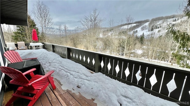 snow covered deck featuring a view of trees