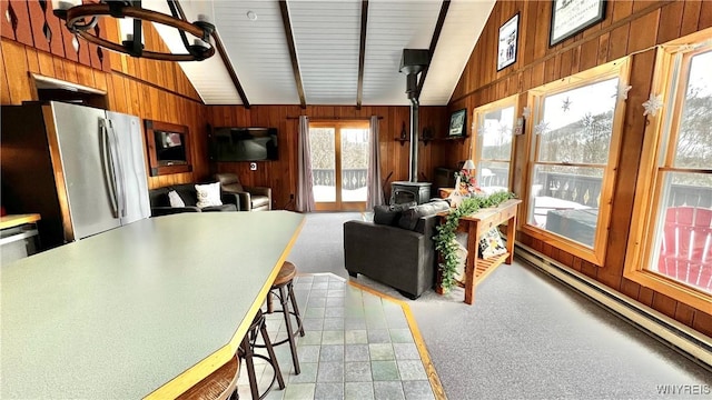 kitchen featuring a wood stove, wood walls, vaulted ceiling, and freestanding refrigerator