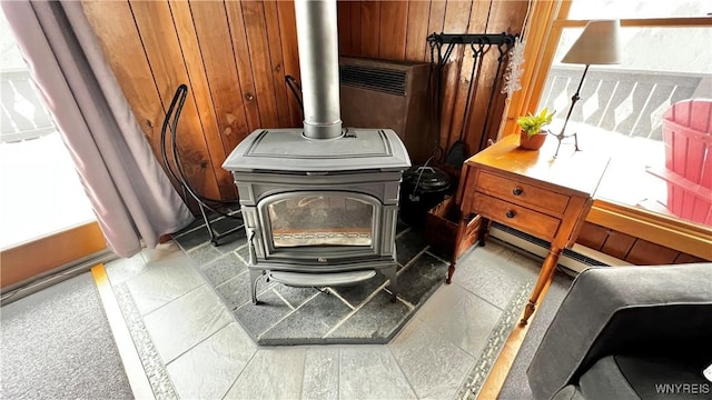 interior details with a baseboard heating unit, wood walls, and a wood stove