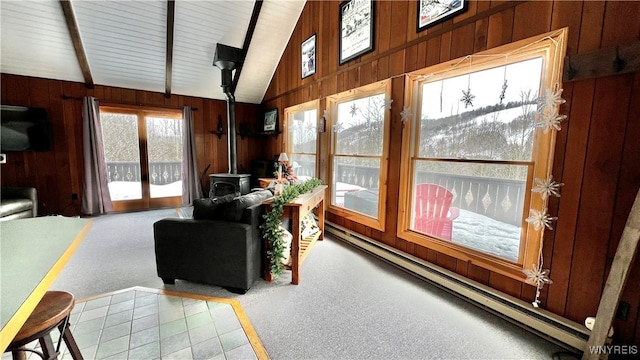 sunroom featuring lofted ceiling with beams, a baseboard radiator, and a wood stove