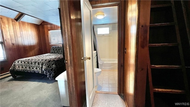 carpeted bedroom featuring ensuite bath, wooden walls, and vaulted ceiling