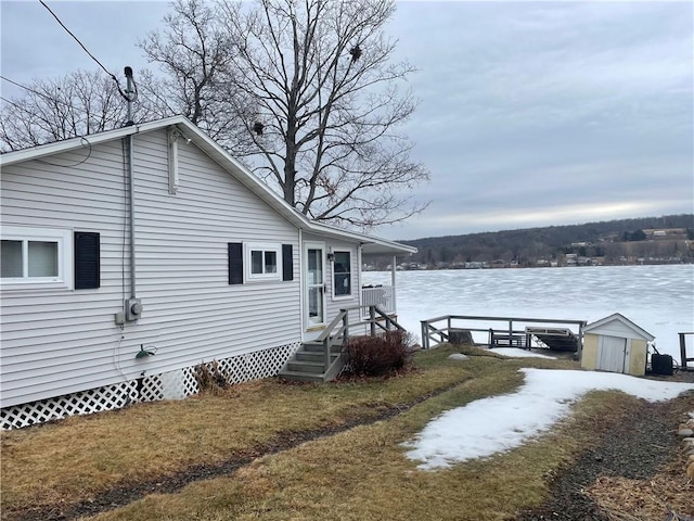 exterior space with a water view, a front lawn, and an outbuilding