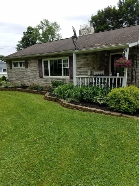 view of front facade with stone siding and a front lawn