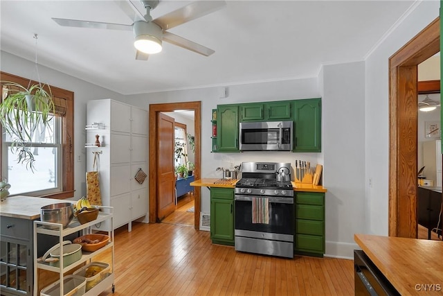 kitchen with green cabinets, stainless steel appliances, light wood finished floors, and wooden counters