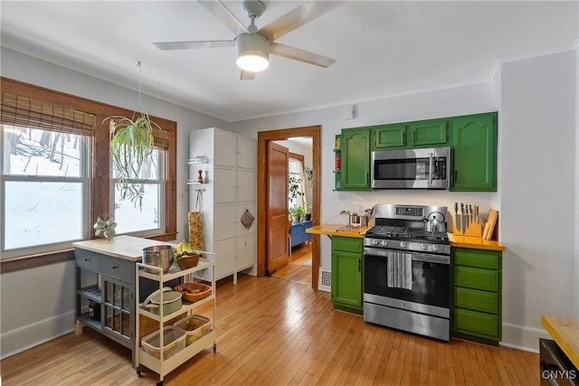 kitchen featuring appliances with stainless steel finishes, light wood finished floors, and green cabinets