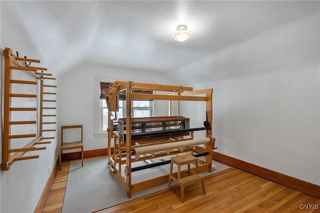 bedroom with light wood-type flooring, lofted ceiling, and baseboards