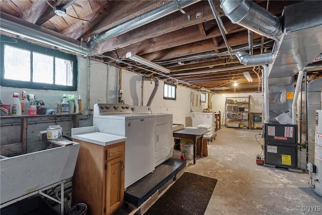 below grade area featuring a sink, washing machine and clothes dryer, and heating unit