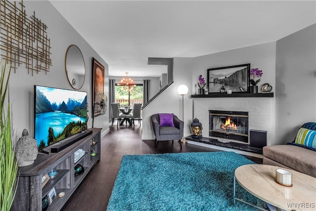 living area featuring a chandelier, a fireplace, and wood finished floors