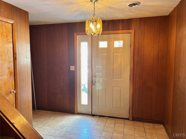 entryway featuring a notable chandelier, wood walls, and light tile patterned floors