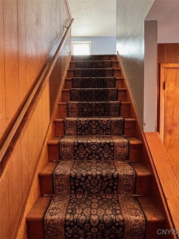 staircase featuring wood walls