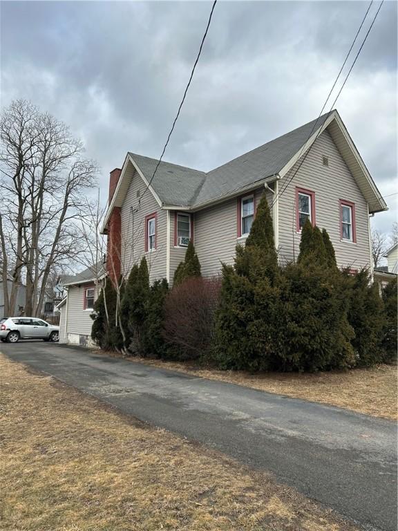 view of side of property with aphalt driveway and a chimney