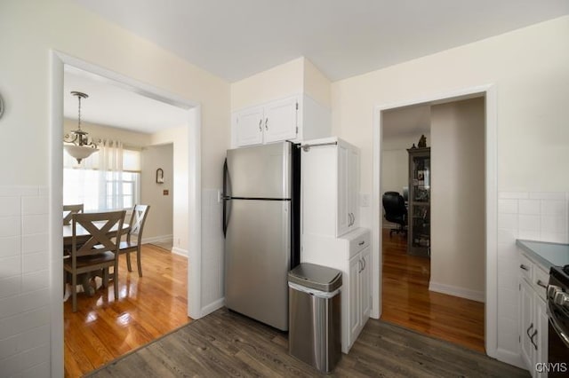 kitchen with dark wood-style flooring, tile walls, freestanding refrigerator, and white cabinetry