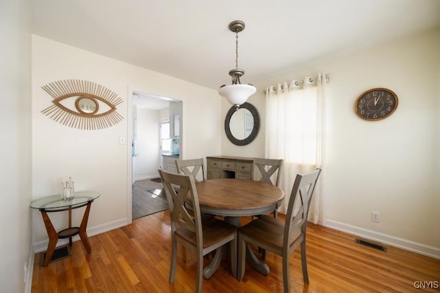 dining area featuring wood finished floors, visible vents, and baseboards