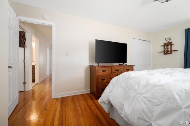 bedroom featuring a closet, light wood-style flooring, and baseboards