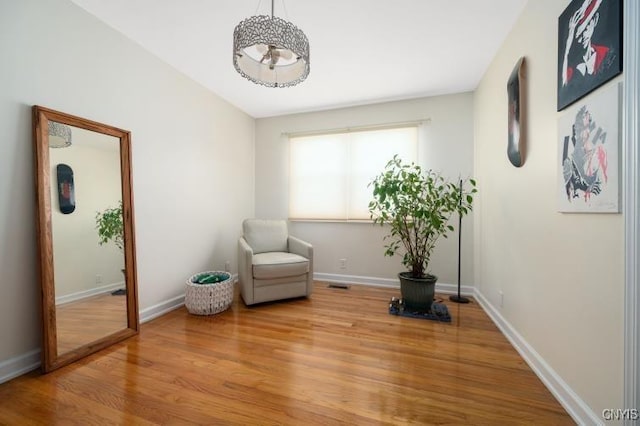 living area featuring visible vents, baseboards, and wood finished floors