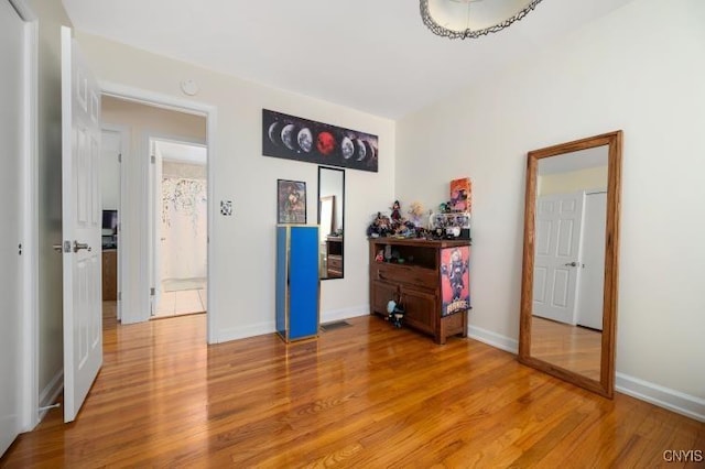 bedroom featuring light wood-style floors, visible vents, and baseboards