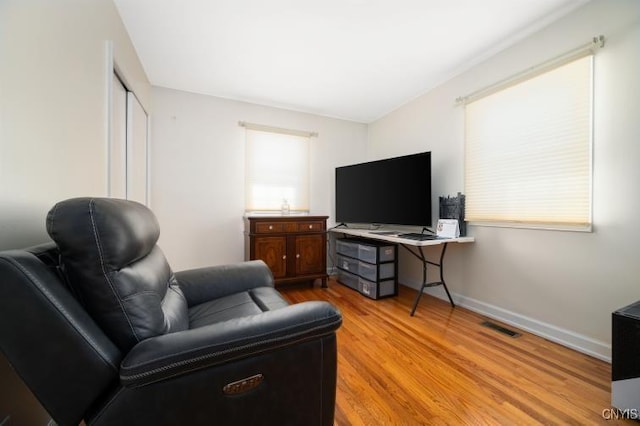 living area featuring light wood-style floors, baseboards, and visible vents