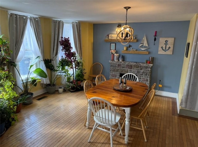 dining area featuring hardwood / wood-style flooring, visible vents, a wealth of natural light, and a stone fireplace