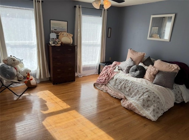 bedroom with a ceiling fan, multiple windows, and hardwood / wood-style floors