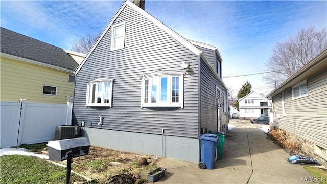 view of side of home with cooling unit and fence