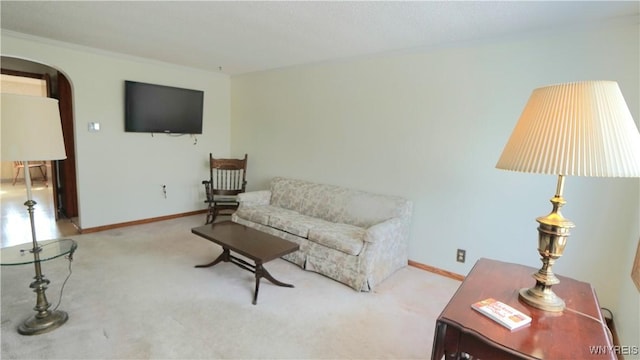 carpeted living area featuring arched walkways and baseboards