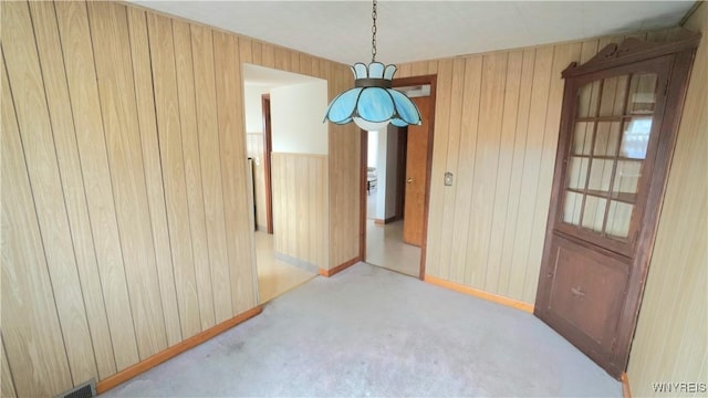 unfurnished room with wood walls, visible vents, and carpet flooring