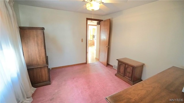 carpeted spare room featuring ceiling fan, visible vents, and baseboards