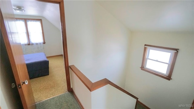 hall featuring carpet, lofted ceiling, and an upstairs landing