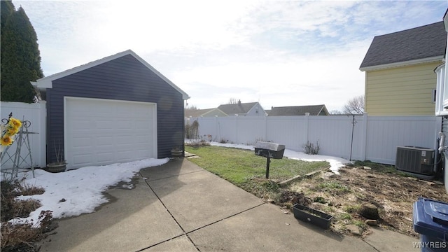 detached garage with driveway, fence, and central air condition unit