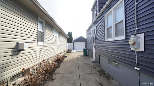 view of side of home with a detached garage, concrete driveway, and an outbuilding