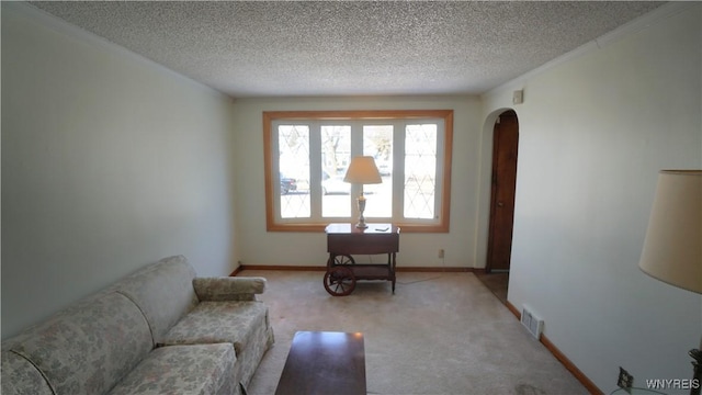 living room with light carpet, visible vents, arched walkways, and a textured ceiling