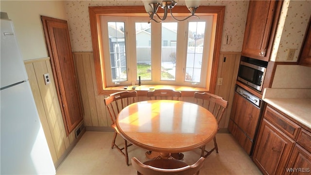 dining space with wainscoting, visible vents, an inviting chandelier, and wallpapered walls